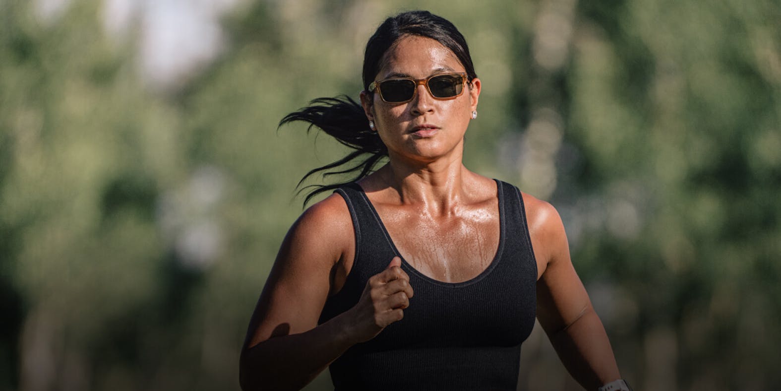 Woman running in black tank top and ROKA sunglasses
