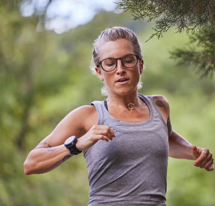 Woman running in grey tank top in the woods