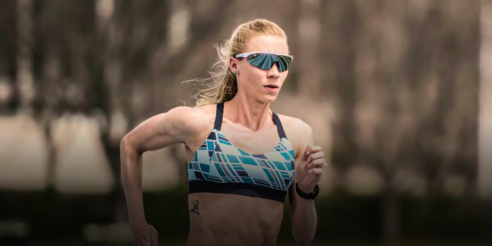 Woman running wearing blue top and ROKA sunglasses