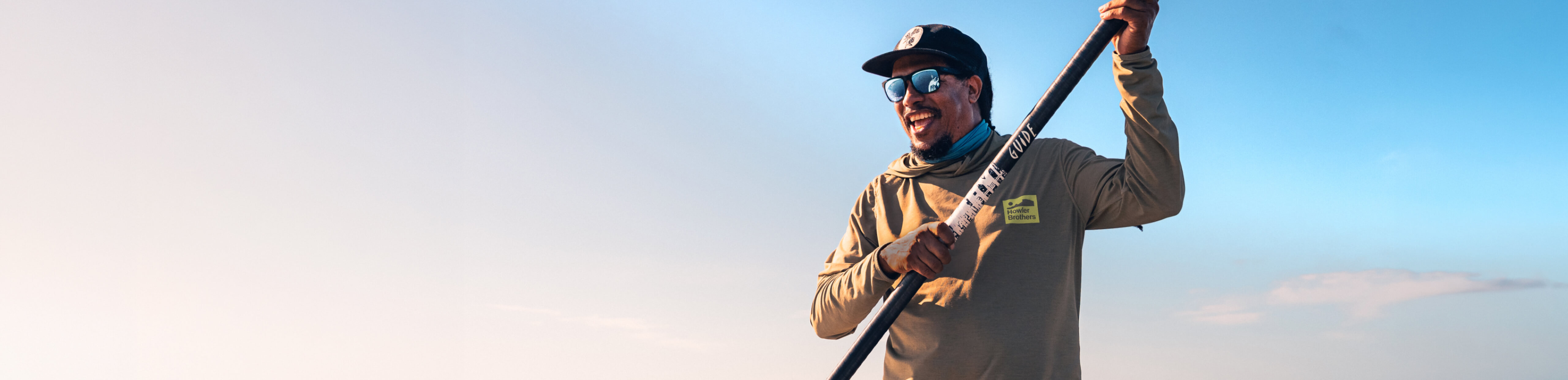 Man smiling while paddle boarding wearing ROKA sunglasses