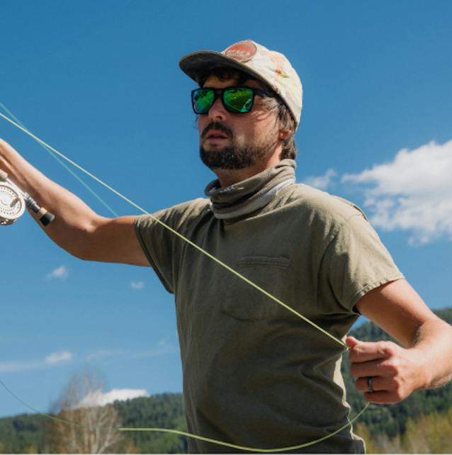 Man pulling on fishing line wearing ROKA sunglasses