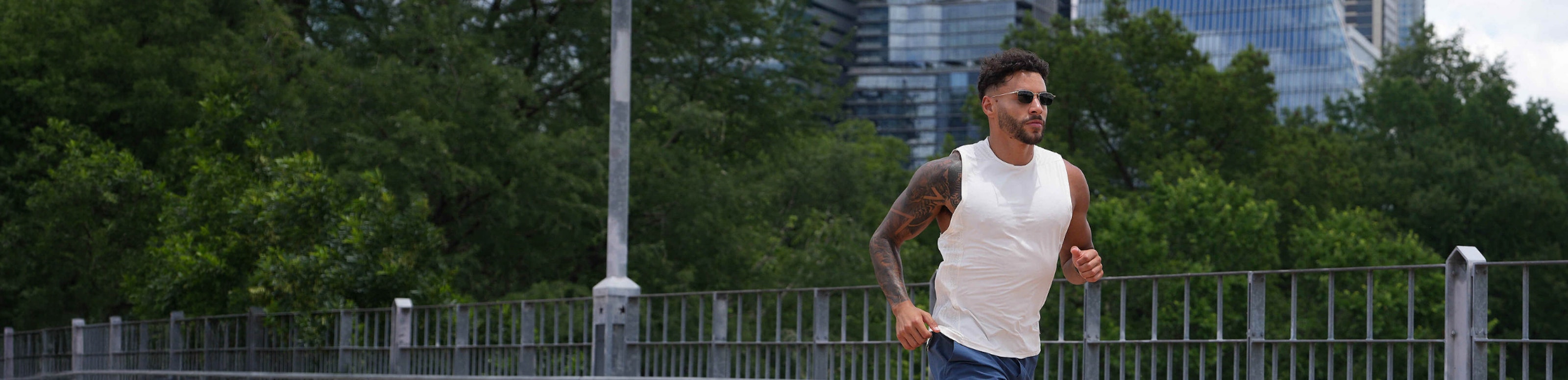 Man jogging over bridge in white tank top