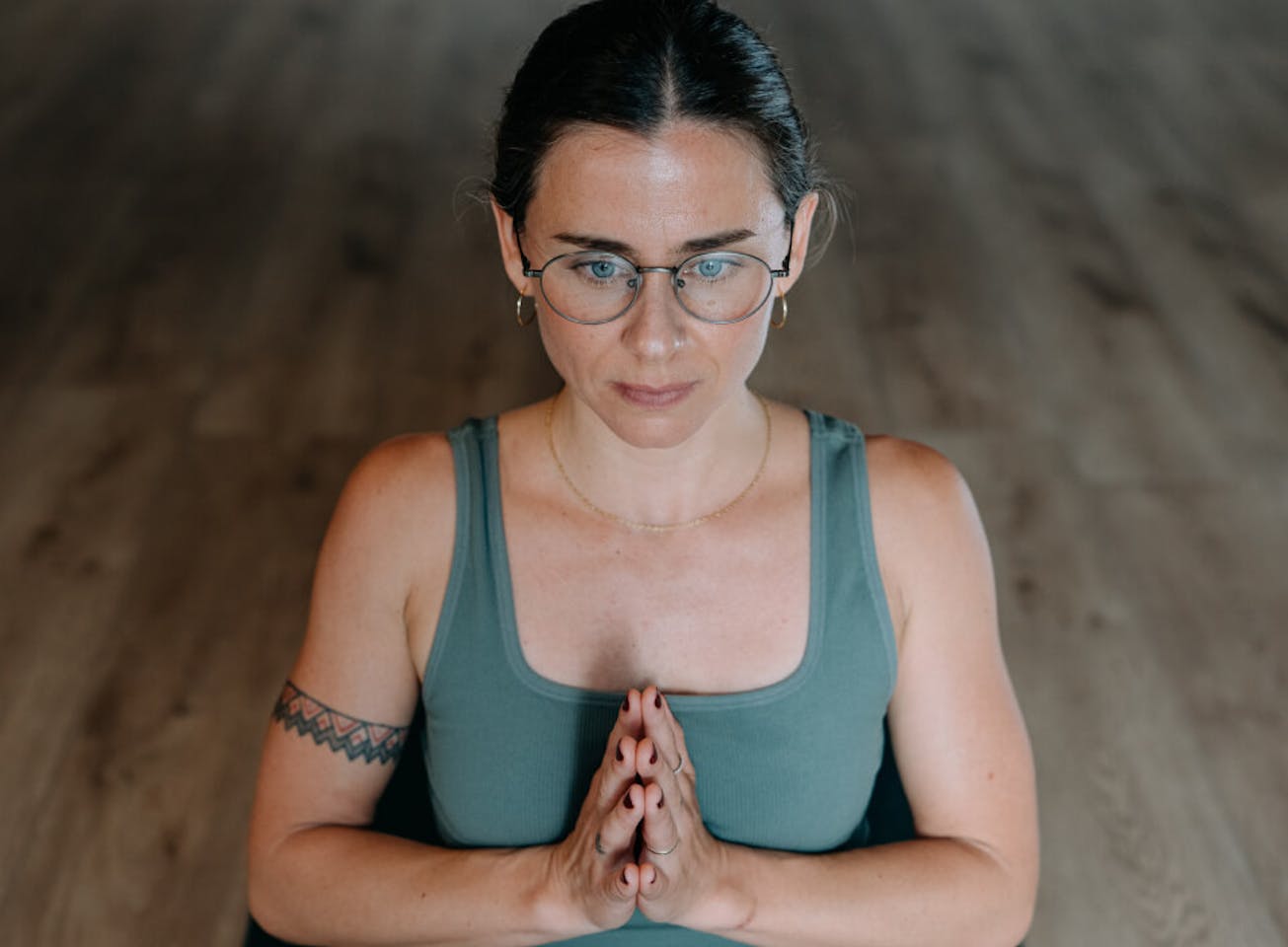 Woman doing yoga pose in green top and Alto Eyeglasses