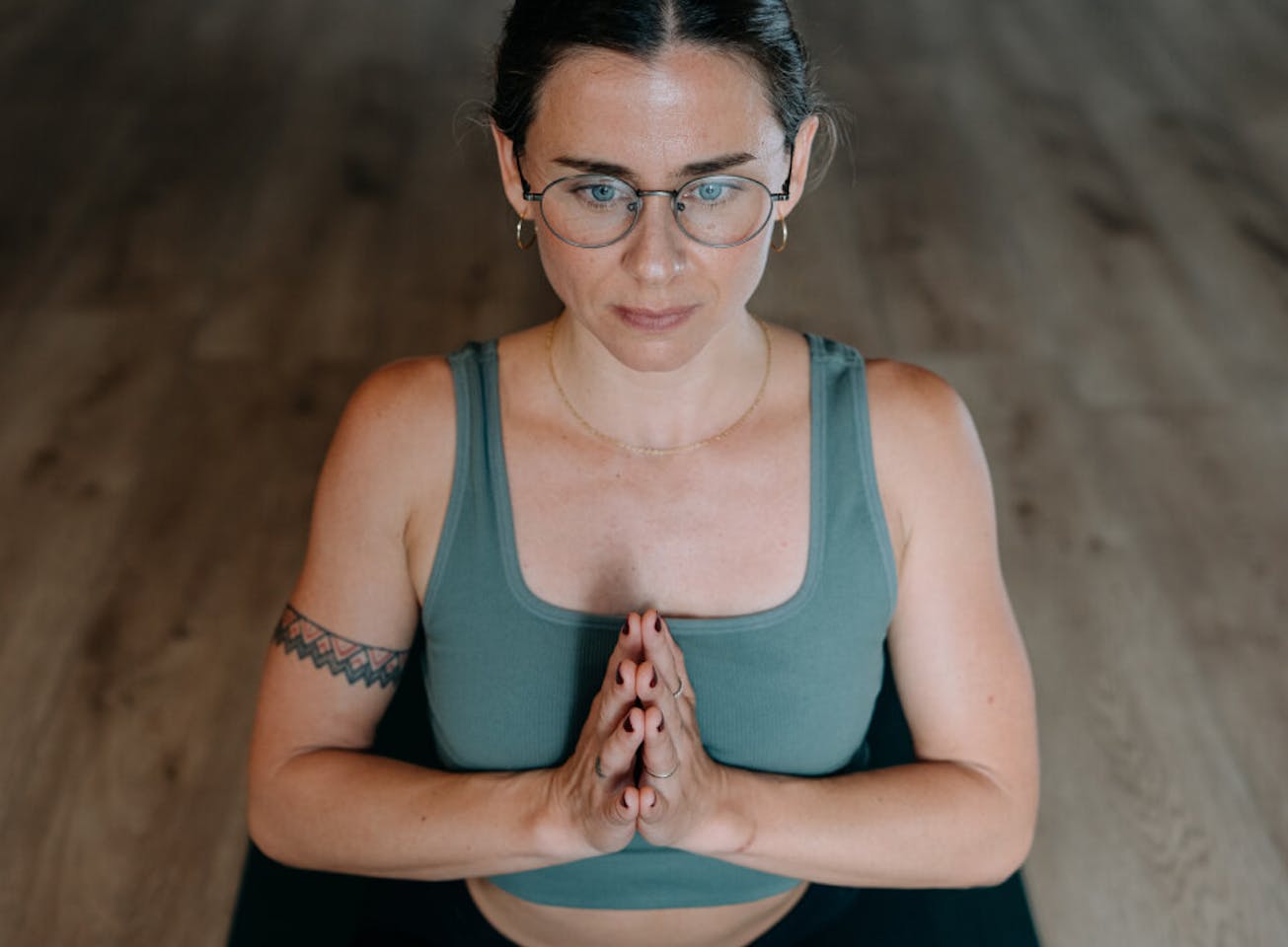 Woman doing yoga pose in green top and Alto Eyeglasses