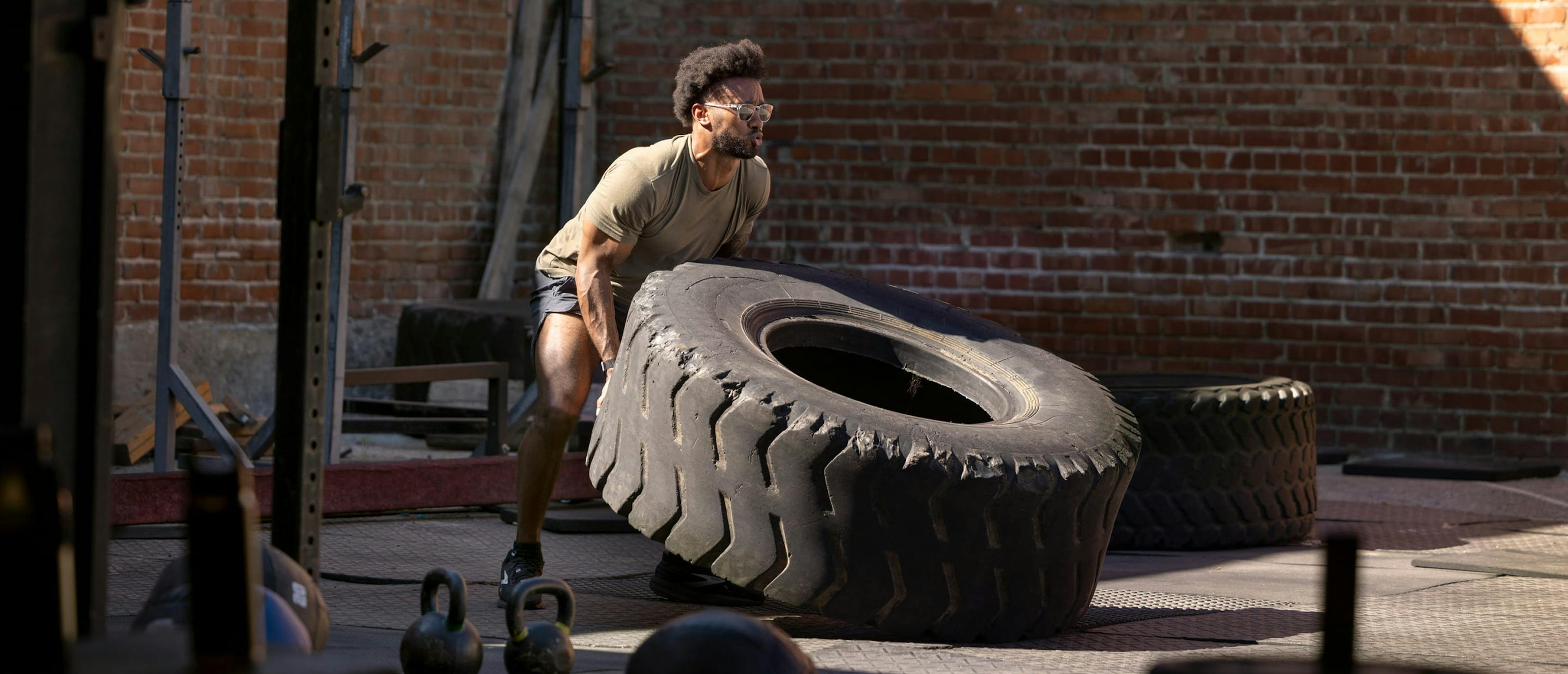 Man flipping large tire in Rory Sunglasses