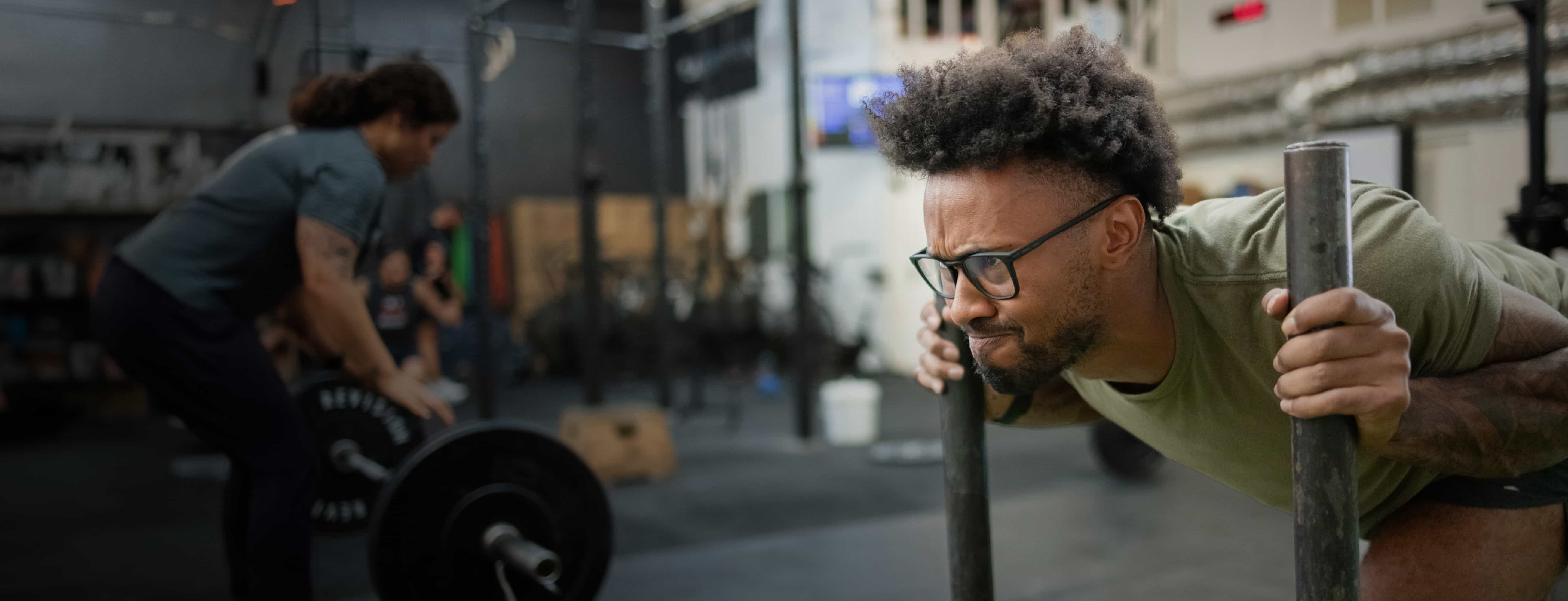 Man pushing weighted sled wearing ROKA eyeglasses