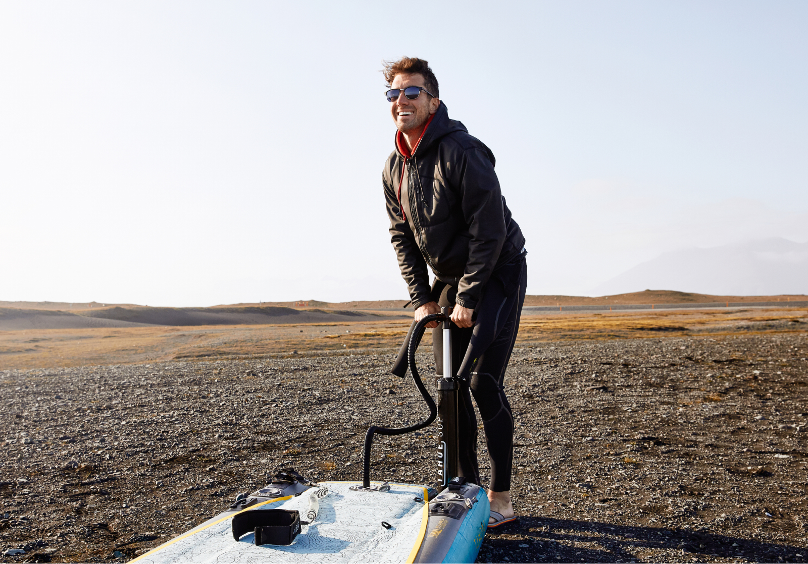 Man pumping air into paddle board wearing Cambridge sunglasses