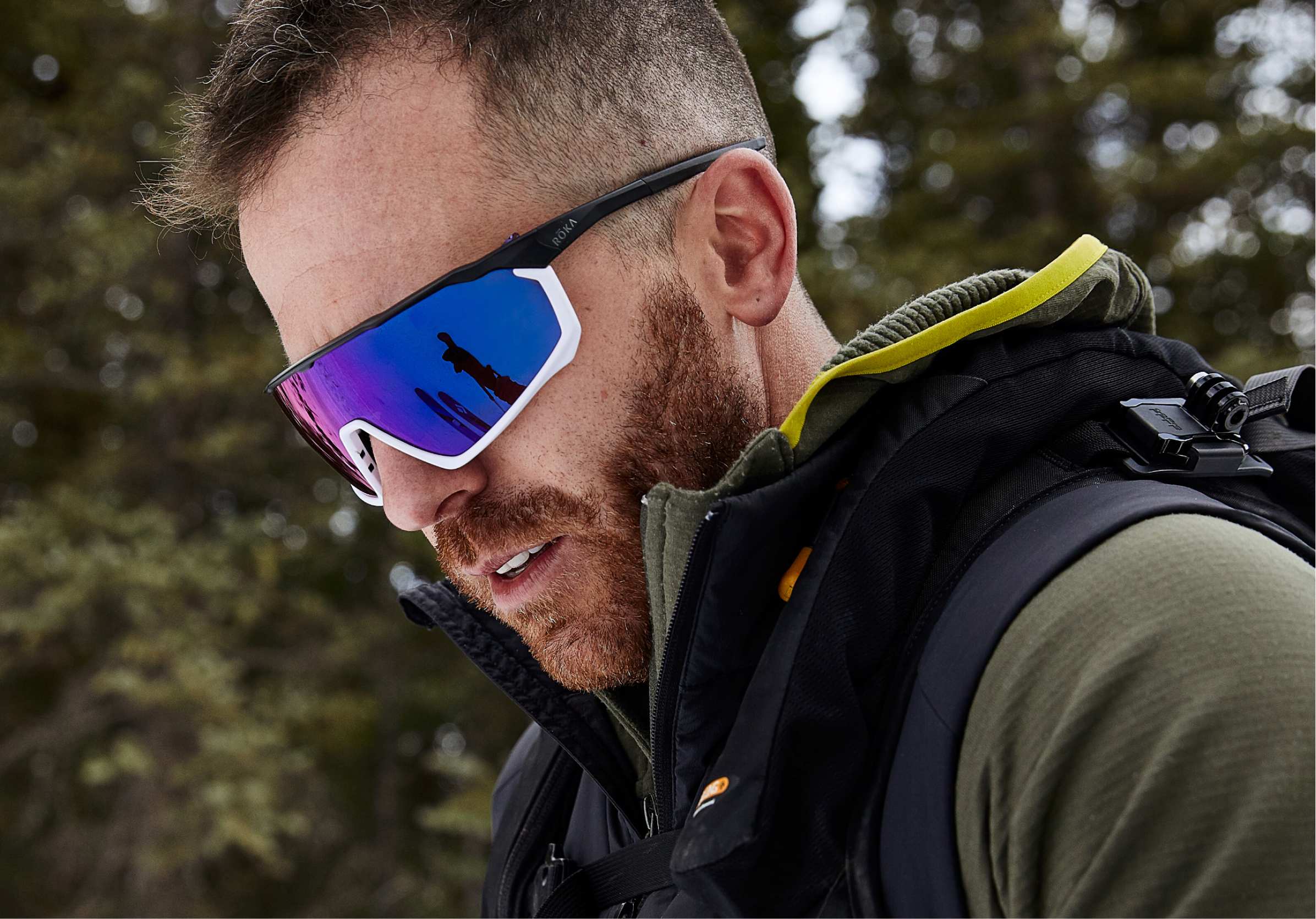 Man in the woods in a green jacket wearing CP-1x sunglasses