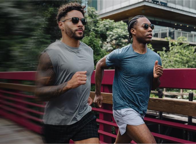 Two men running on bridge wearing ROKA sunglasses