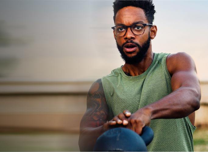 Man swinging kettlebell in green tank top